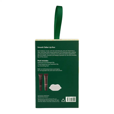 Back view of a dark green lip duo retail box with a matching green hanging loop, shown on a plain white background. The box includes product description, pack contents, and a barcode.