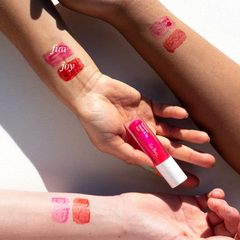Swatches of Joy & Fun shades of beetroot cheek & lip tint on arms with different skin tones.