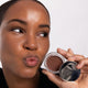 Woman holding a Ere Perez Cacao Bronzing Pot - Costa 7.5g makeup product.