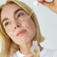 Woman applying the face nectar oil to her cheek.