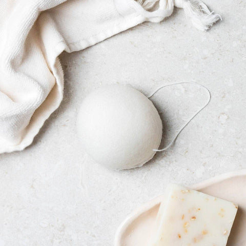 Original konjac sponge pictured on a bathroom surface next to a face towel.