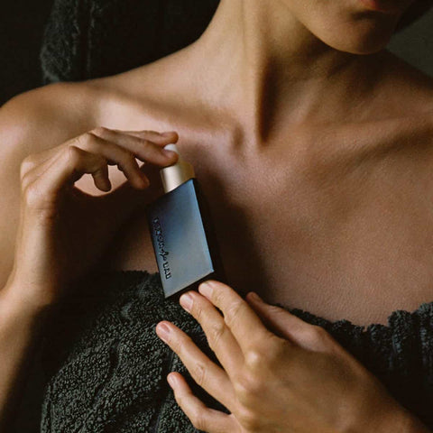 Person in a towel holding a bottle of eye of horus regenerative night serum after showering.
