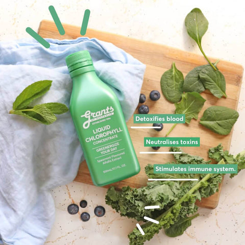 Green bottle of Liquid Chlorophyll on a wooden board with leaves and berries.