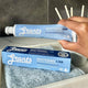 Hand holding a tube of Grants Whitening +HA toothpaste with packaging in the foreground.