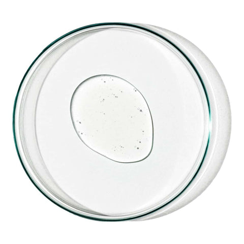Swatch of gel facial cleanser in a glass dish on a white surface.