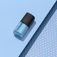 Blue nail polish bottle with black cap on a light blue background
