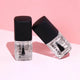 Two nail polish bottles with black caps on a pink background