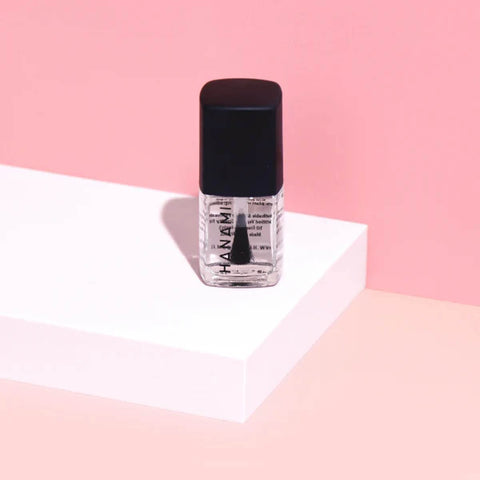 Nail polish bottle with black cap on a pink and white background