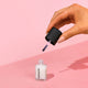 Hand applying Hanami nail polish to a pink background