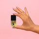 Hand holding a small bottle of Hanami nail polish against a pink background