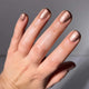 Hand with rose gold nail polish on a neutral background