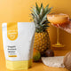 Happy Way Vegan Protein Water package with a cocktail, pineapple, and mango on a yellow background.