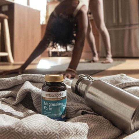 Herbs of Gold Magnesium Forte supplement bottle on a blanket with a water bottle in the background.