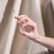 Hand holding a small white object against a neutral background.
