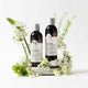 Two bottles of shampoo and conditioner with flowers on a white background.