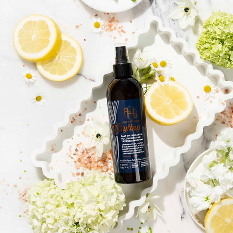 Bottle of 'Futura' hair product on a decorative plate with lemons and flowers.