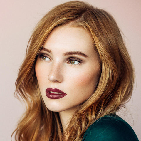 Young woman with fair, freckly skin tone & dark blonde hair wearing bordeaux rouge lipstick.