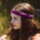 Person with auburn hair wearing wild beet twist headband with it scrunched & twisted for a bit of flair.