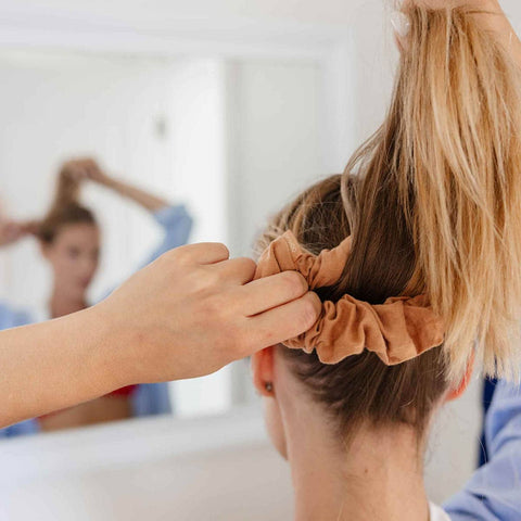 Person tying Kooshoo's Plastic Free Macchiato Brown Scrunchie around her ponytail.
