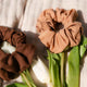Two brown scrunchies on a piece of soft fabric with white tulips and leaves.