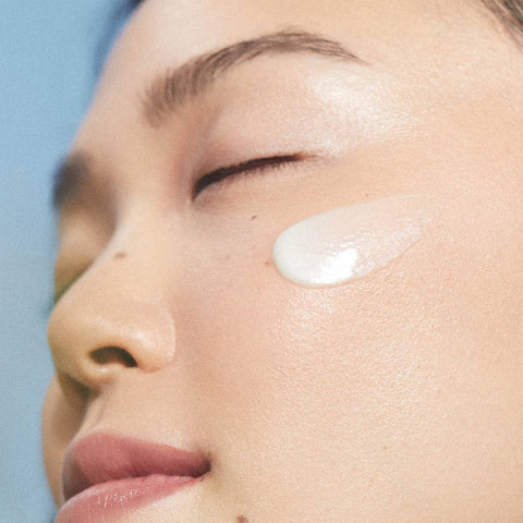 Model wearing a swatch of creamy, thin, green tinted moisturiser. 