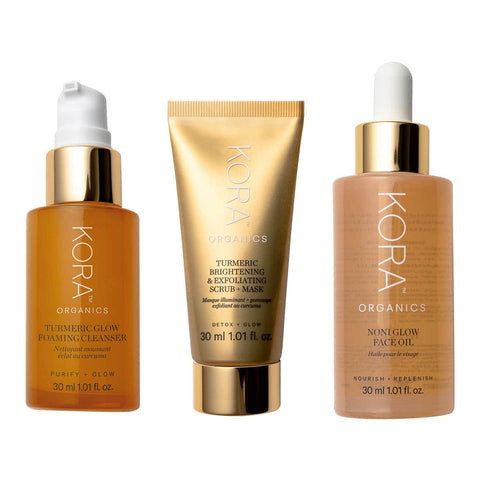 Kora Organics Turmeric Glow Cleanser, Turmeric Brightening & Exfoliating Scrub + Mask and Noni Glow Face Oil in gold, white & yellow packaging.
