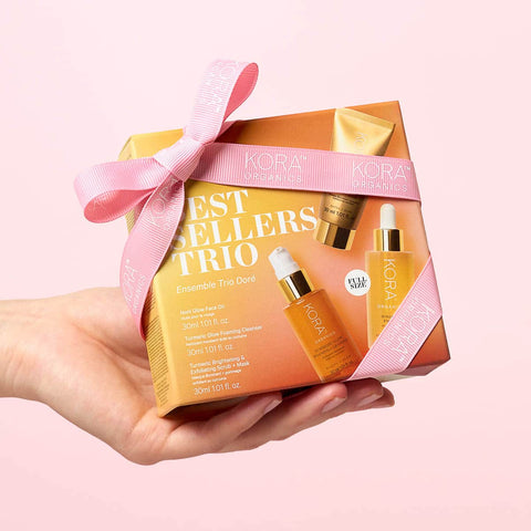 Hand holding Best Sellers Trio Box with a pink ribbon and a pale pink background. 