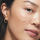 Close-up of a model wearing a swatch of the face serum on their cheek.