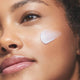 Close-up of a woman wearing a swatch of Plant Stem Cell Retinol Alternative Moisturizer on her cheek.