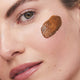 Close-up of a woman's cheek with a swatch of the turmeric mask.