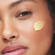Close-up of a woman with a swatch of Turmeric Glow Moisturizer on her cheek.