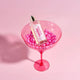 Lavanila Vanilla Grapefruit 150ml bottle in a pink glass with pink pearls on a pink background.