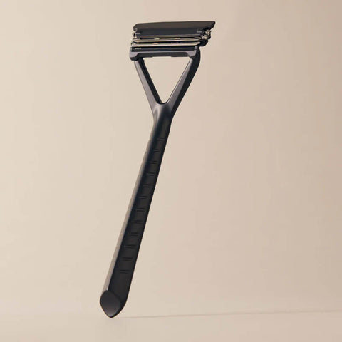Black double-edged safety razor on a beige background