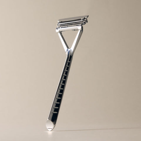 Metallic razor on a beige background
