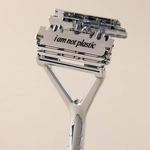 Metallic razor with 'i am not plastic' text on a beige background