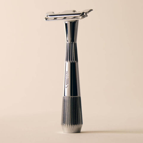Silver safety razor on a beige background