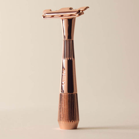 Rose gold safety razor on a beige background
