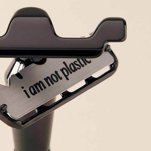 Safety razor with 'i am not plastic' text on a beige background