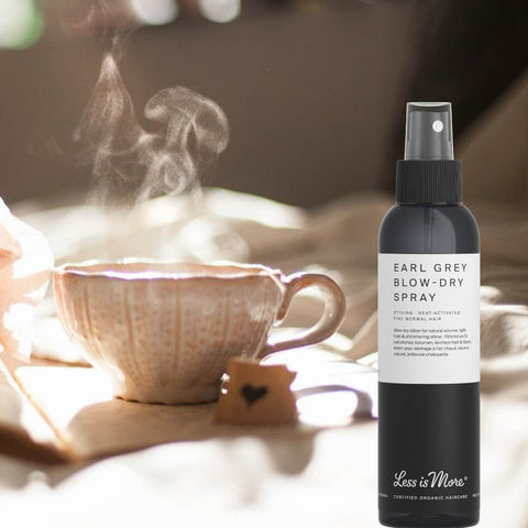 Earl Grey Blow-Dry Spray bottle with a steaming cup of tea in the background