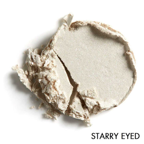 Close-up of pale glittery beige pressed eye shadow with 'Starry Eyed' text on a white background