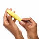 Yellow bullet massager held by two hands against a white background.