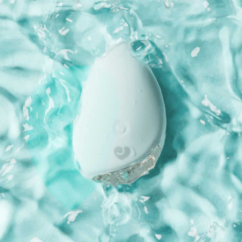 Light blue silicone personal massager partly submerged in water with a blue background.