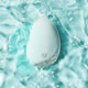Light blue silicone personal massager partly submerged in water with a blue background.
