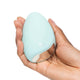 Light blue egg-shaped personal massager held in a hand against a white background.