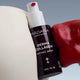 MADARA Derma Collagen Peptides Serum bottle held between red & white design elements.