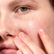 Close-up of a person's eye and finger touching skin