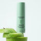 Mádara Exosome skincare serum bottle with a green apple on a white background.