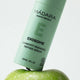Mádara Exosome serum bottle on a green apple with a white background.