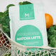 Matcha Maiden Supergreens Matcha Latte package with green vegetables in the background