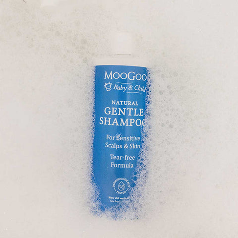Blue bottle of Moogoo Baby & Child Gentle Shampoo in a bubble bath.